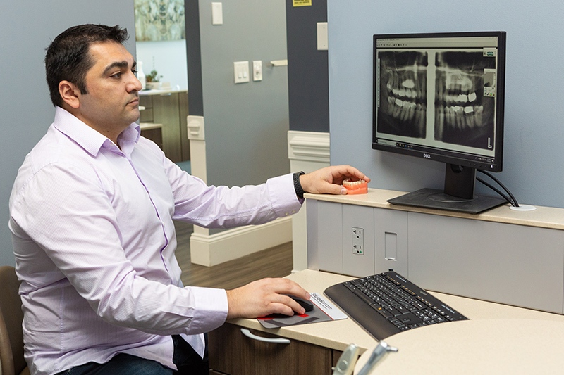 Dr. Armen Balasanyan examining a patient’s dental x-ray in preparation for dental implants